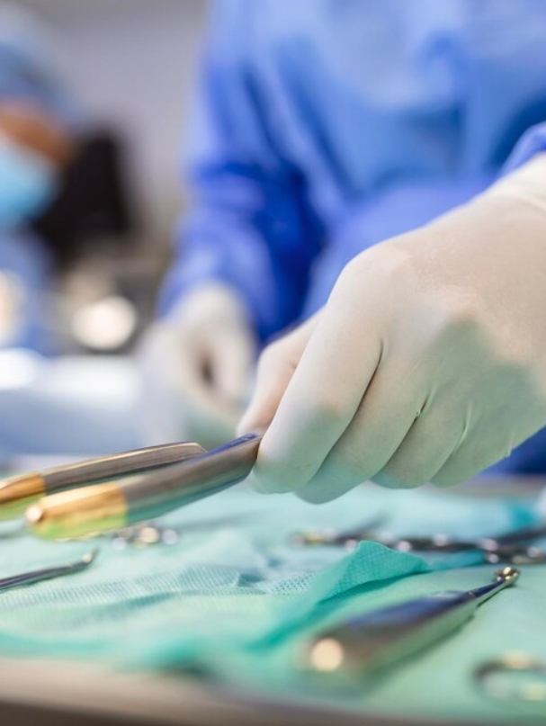 nurse-hand-taking-surgical-instrument-group-surgeons-background-operating-patient-surgical-theatre-steel-medical-instruments-ready-be-used-surgery-emergency-concept_657921-1109